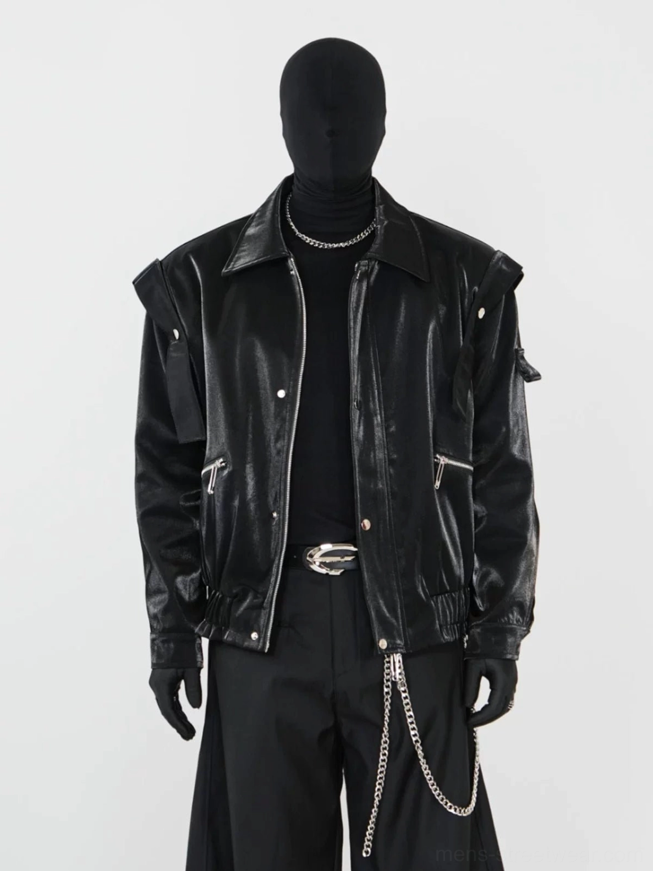 Black glossy modular biker jacket styled with a black turtleneck, silver necklace, tailored trousers, and detachable shoulder details