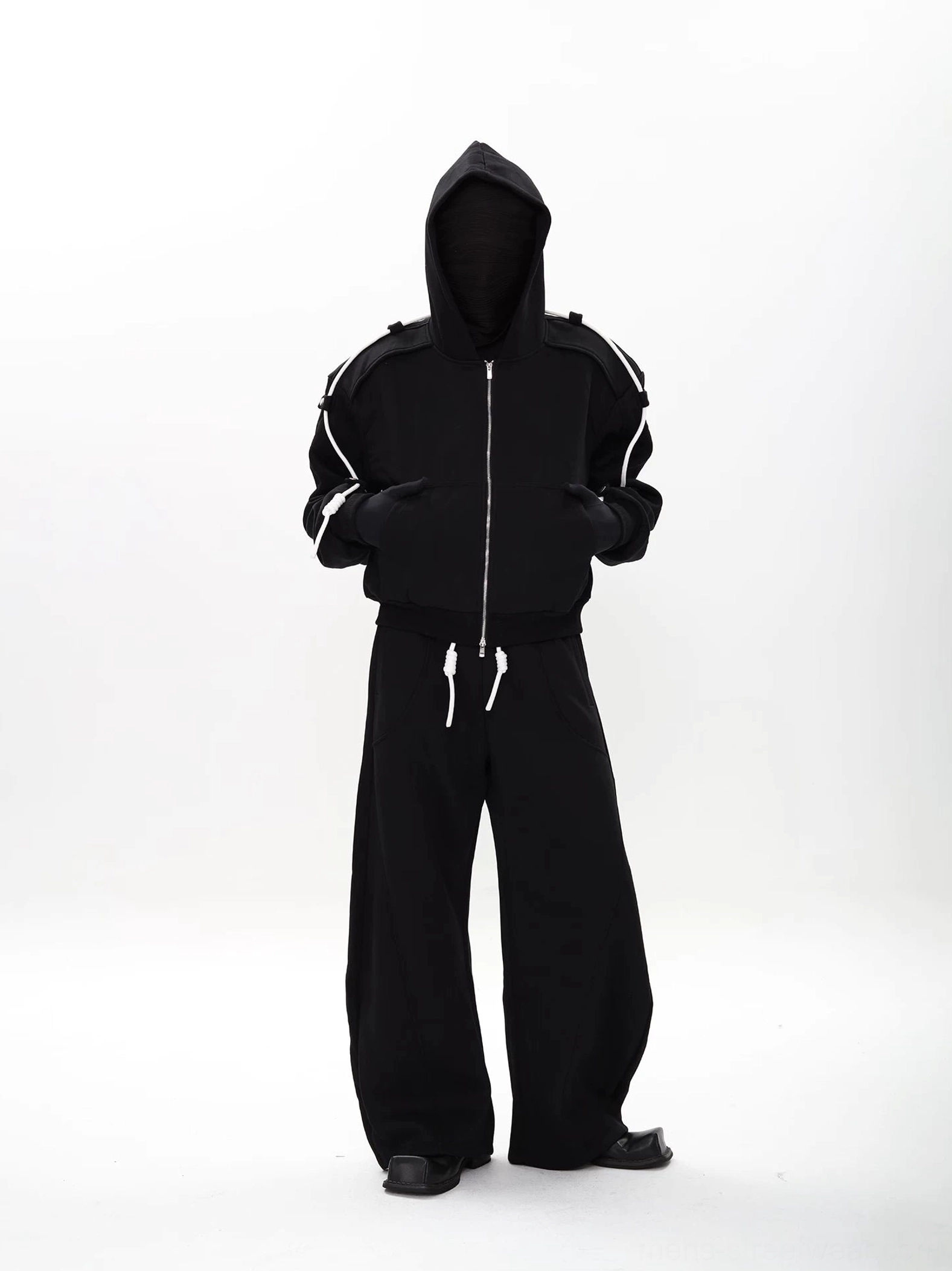 Black modular zip-up hoodie and wide-leg sweatpants set with contrast white drawcords, shown in a front full-body streetwear look