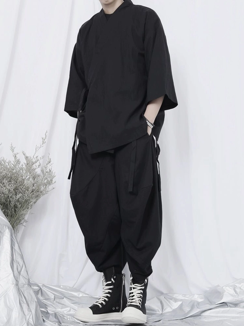 Minimalist black streetwear outfit featuring a basic crew neck tee and loose harem pants in a monochrome urban style