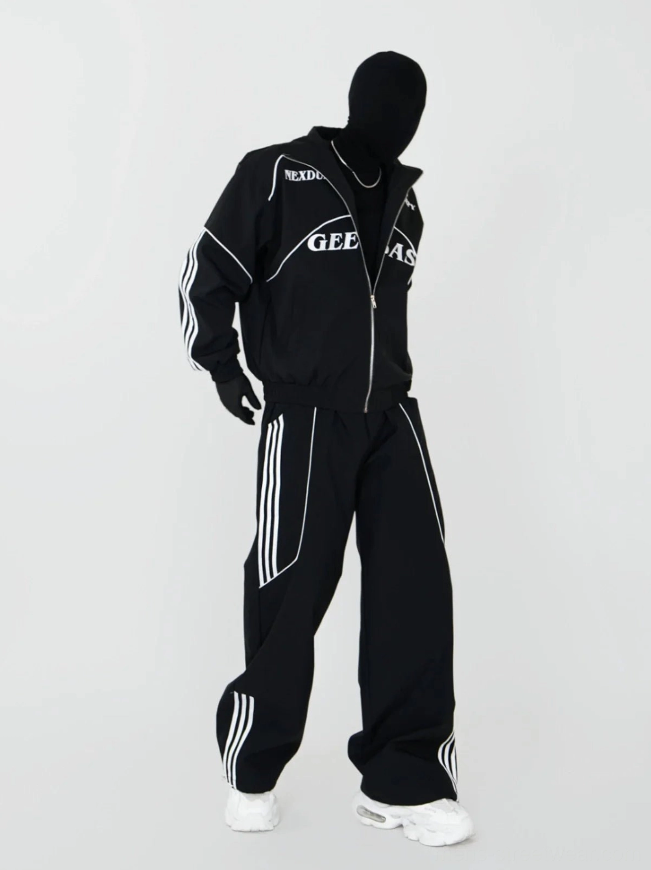 Three-quarter front view of black moto-inspired zip track jacket and loose striped wide-leg track pants