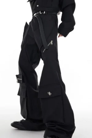 Low-angle side view of black multi-pocket flared cargo trousers with cargo flap pockets, metal zipper accents, leather belt, and black boots