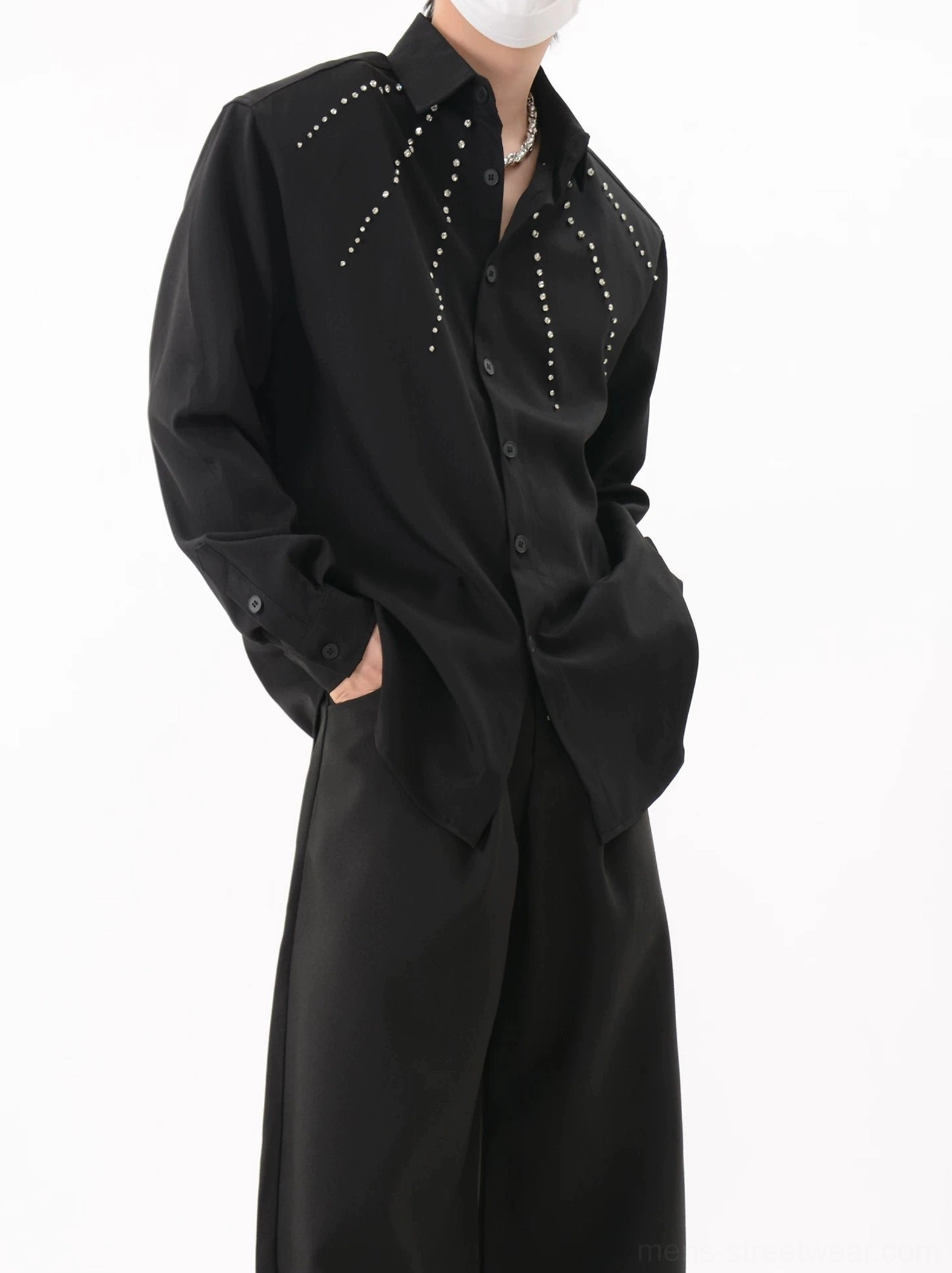 Black Nova Burst studded overshirt shown in a three-quarter view with silver radial rivets, open button styling, and wide-leg streetwear trousers