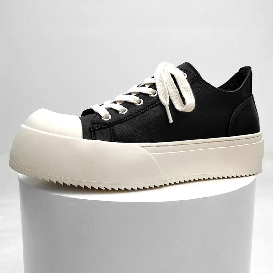 Black and off-white chunky platform low-top sneakers displayed on a white stand with flat white laces, matte upper, rounded toe cap, and serrated thick sole