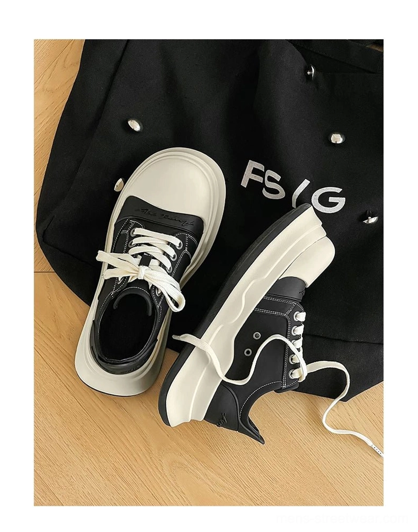 Flat lay display of black and off-white chunky platform sneakers with white laces, oversized toe caps, and a black tote bag styling prop