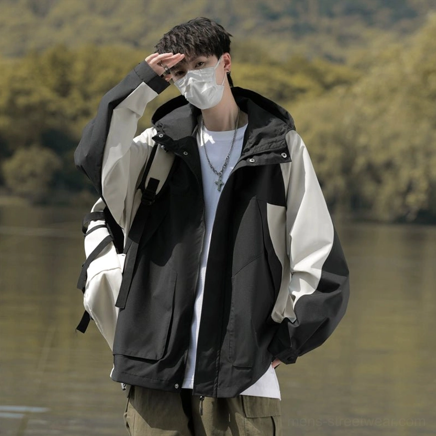 Front view of black and off-white oversized colorblock windbreaker jacket with adjustable drawcord hood and flap pockets