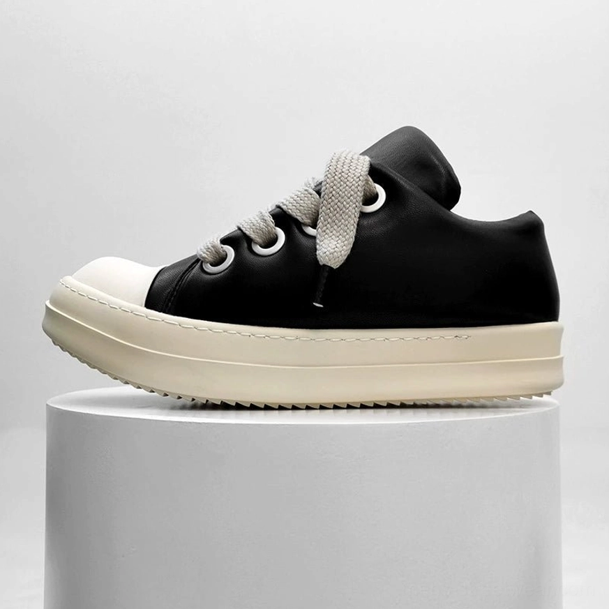 Front three-quarter product view of black and off-white platform sneakers on a pedestal, highlighting the leather texture, lace-up design, rounded toe, and chunky sole