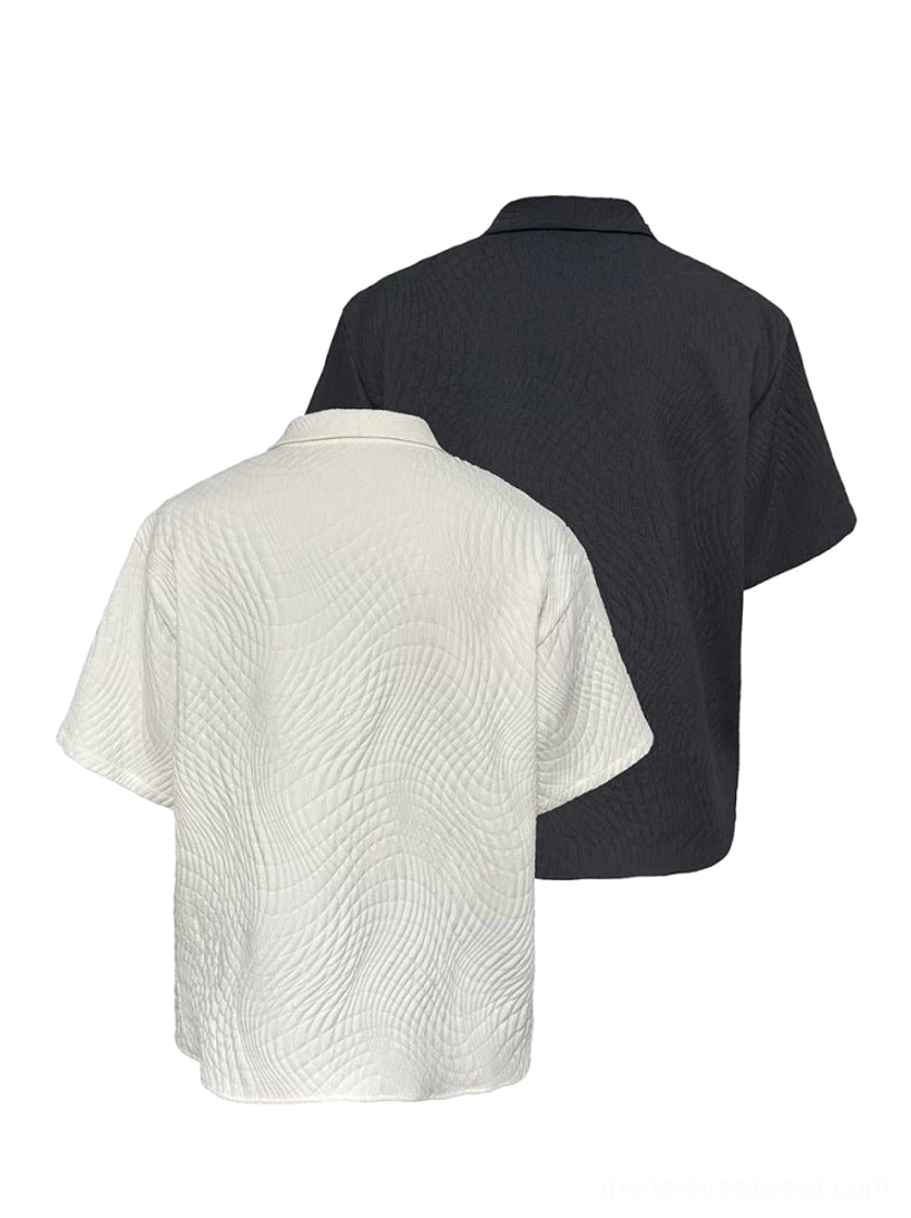 Flat lay display of black and off-white textured quilted camp collar shirts with matching button fronts