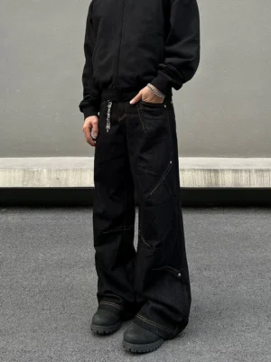 Front view of black orbit panel wide-leg utility jeans with contrast stitching, metal waist chain and workwear boots
