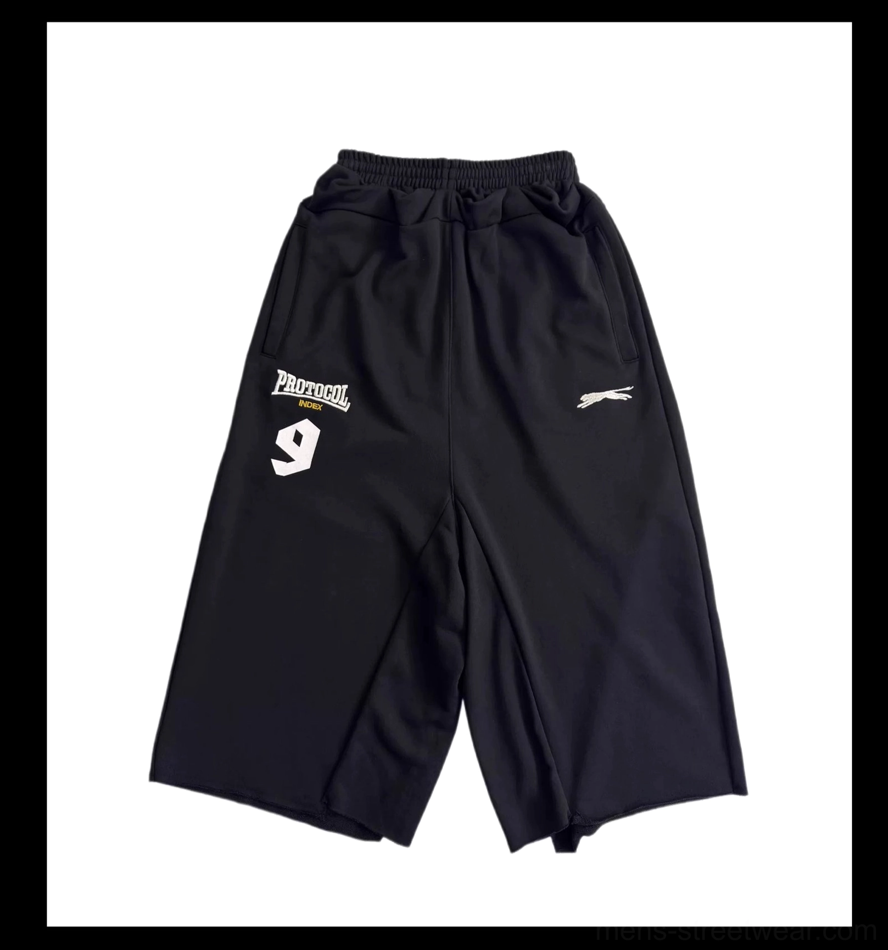 Flat lay front view of black oversized 7/8 court shorts with clean flat hems, elasticated waistband, and streetwear thigh graphic