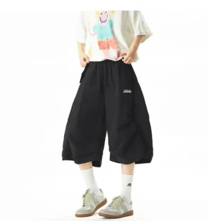 Front view of black oversized balloon nylon jogger shorts with wide cropped legs elastic drawstring waist and embroidered waistband logo
