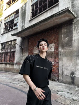 Black oversized chain-lace shoulder graphic tee styled with black trousers in an industrial punk techwear streetwear outfit