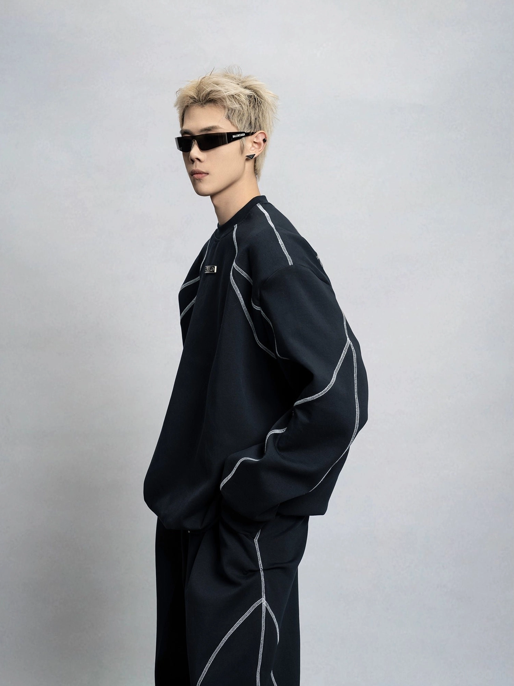 Three quarter front view of a black oversized contrast stitch crewneck sweatshirt with dropped shoulders, chest embroidery, and matching streetwear trousers