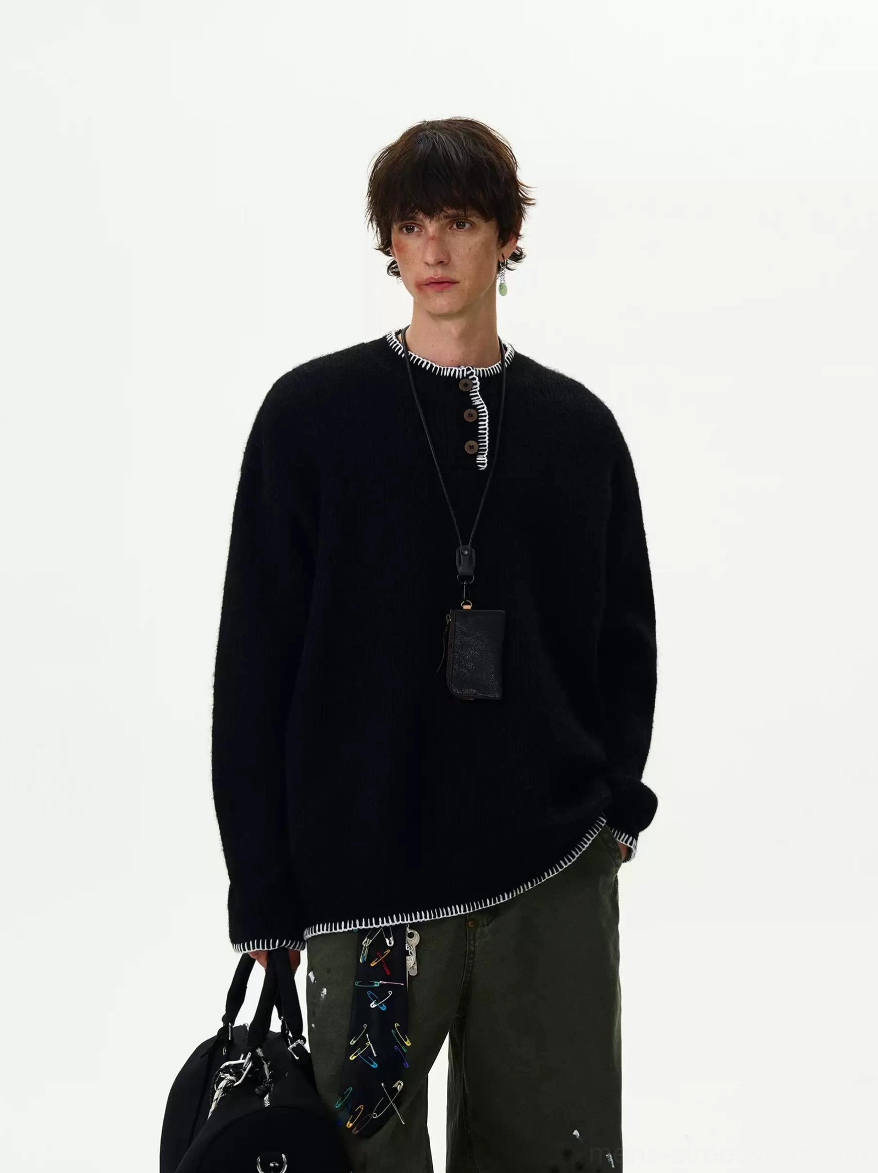 Black oversized contrast-stitch Henley knit sweater styled with green cargo trousers and a leather crossbody pouch