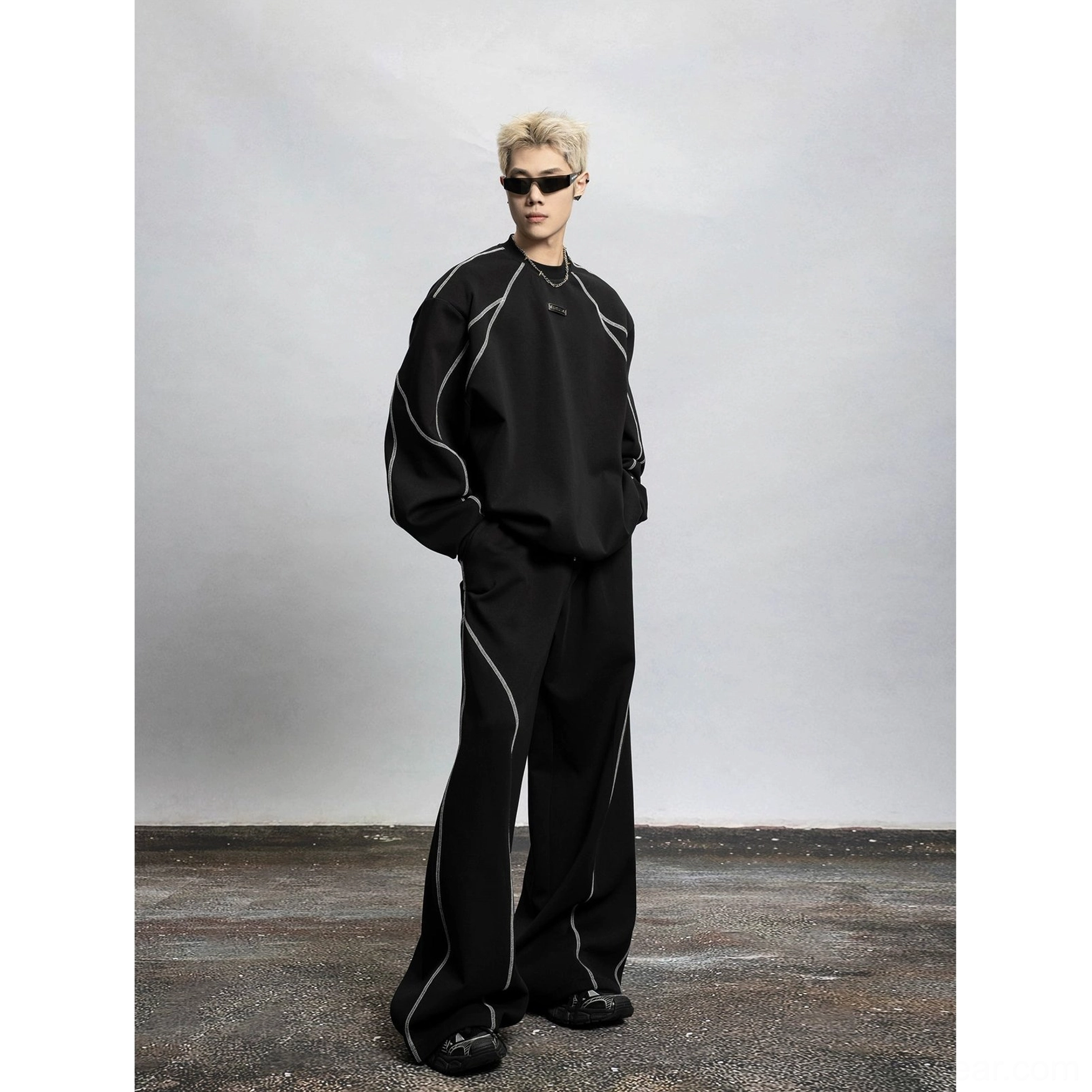 Full front view of a black oversized contrast stitch crewneck sweatshirt with visible seam lines, relaxed streetwear fit, and coordinated wide leg pants