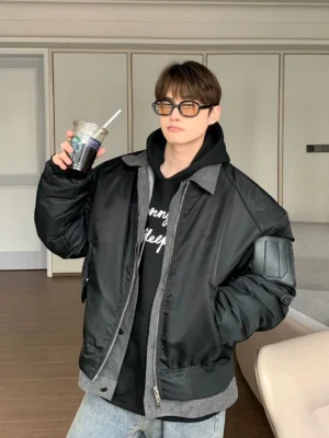 Black oversized contrast trim zip bomber jacket with faux layered grey hem and utility sleeve pocket worn in a modern indoor streetwear look
