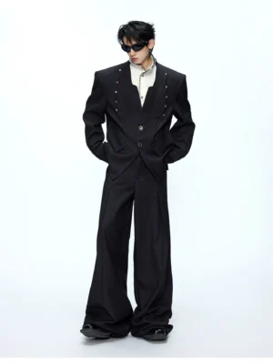 Black oversized deconstructed blazer and wide-leg trousers worn by male model in white studio front view