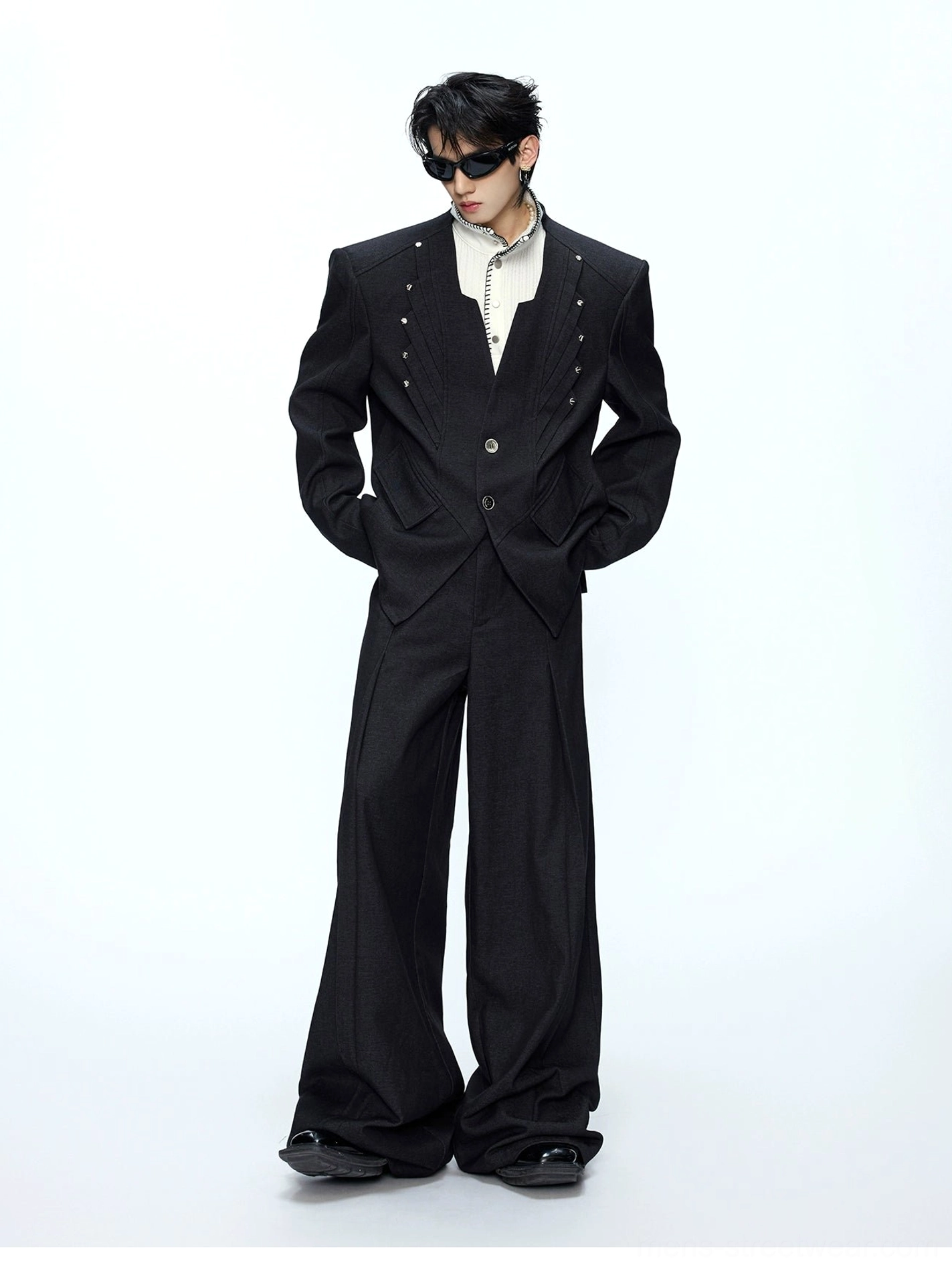 Black oversized deconstructed blazer and wide-leg trousers worn by male model in white studio front view