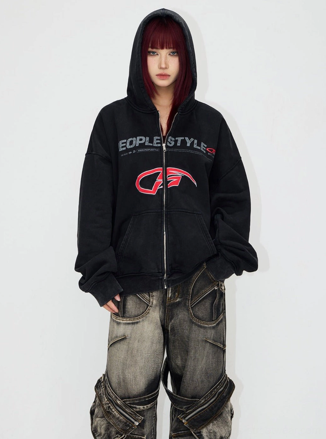Close front view of a black oversized distressed hooded streetwear jacket with full zipper, front pockets, and washed texture