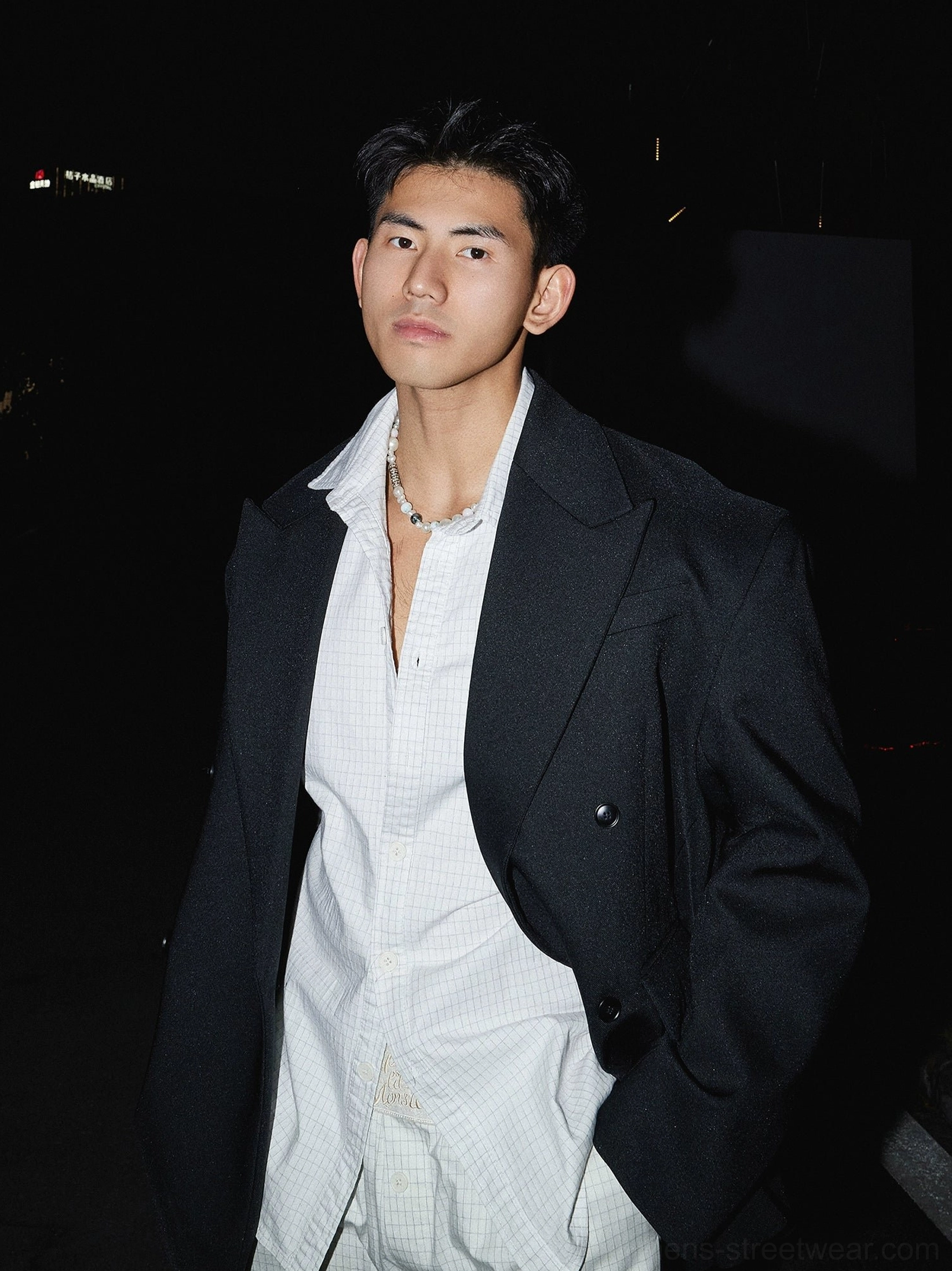 Black oversized double-breasted blazer layered over a white grid shirt in a nighttime Korean streetwear outfit