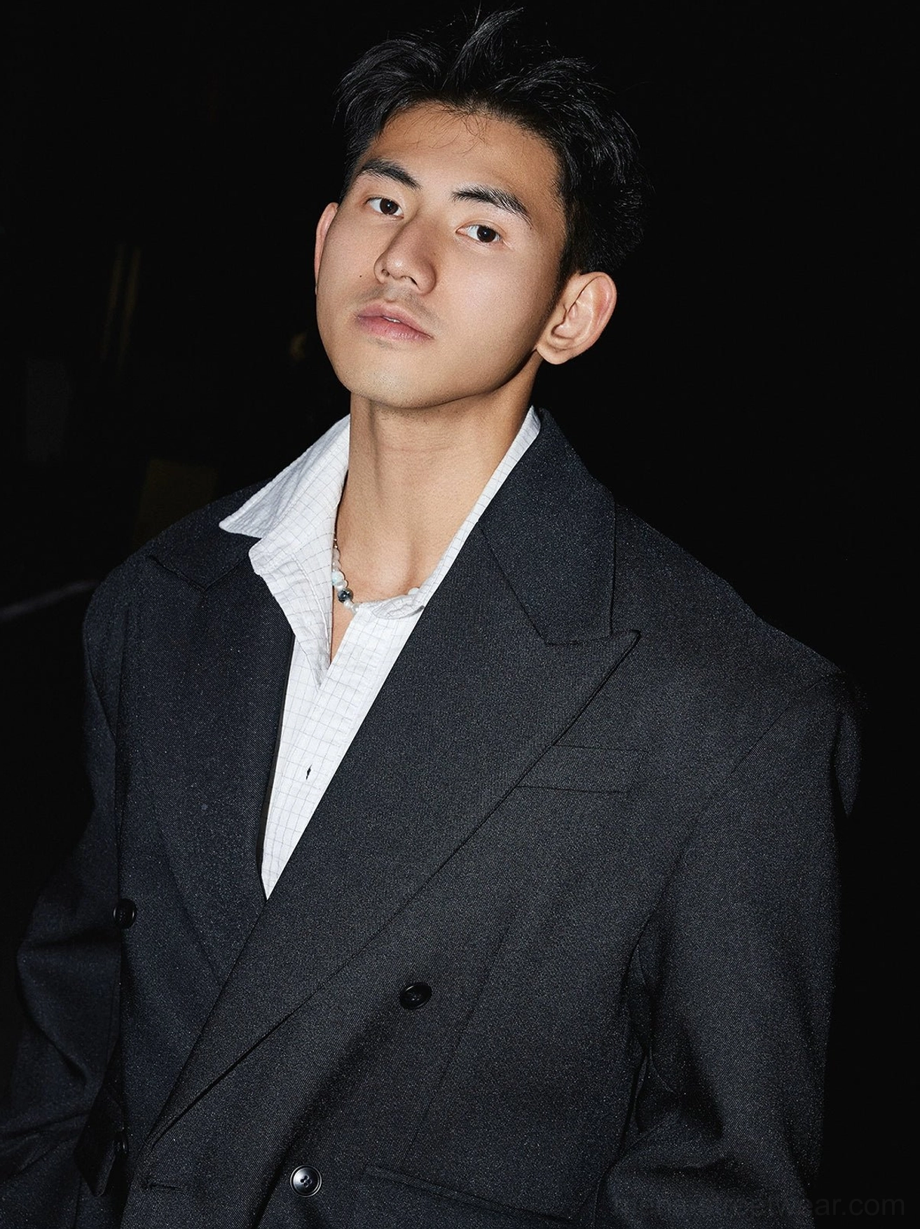 Close-up front view of black oversized double-breasted blazer with metal buttons, notched lapels and smooth tailored fabric