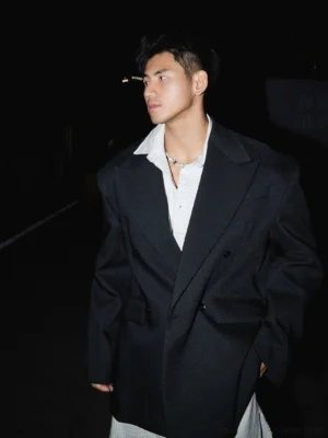 Black oversized double-breasted blazer in a left three-quarter view, styled on a male model for nighttime Seoul streetwear