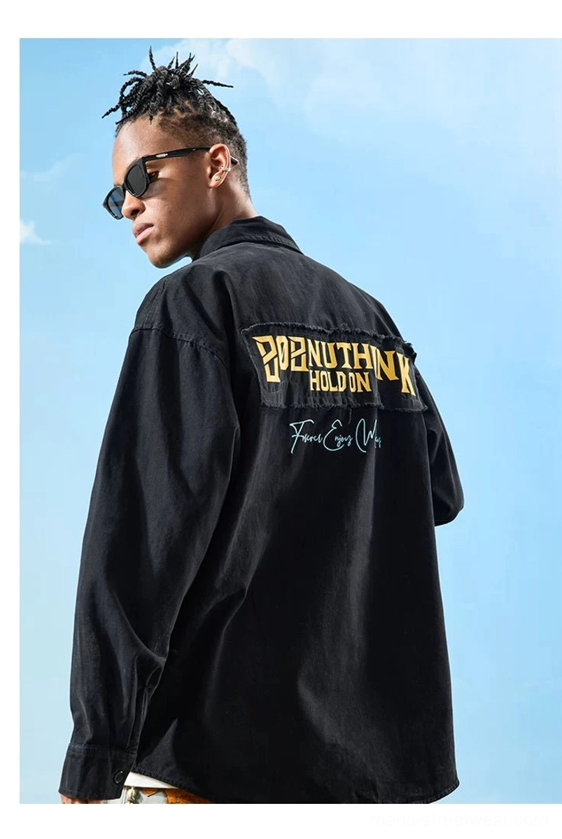Black oversized embroidered button-up shirt shown from the rear with yellow back embroidery and frayed patch styled with cargo pants