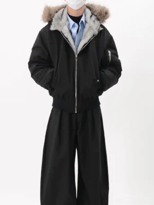 Black oversized faux fur lined hooded bomber jacket front view styled with blue shirt and black wide-leg trousers