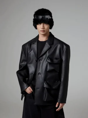 Front close-up of black oversized faux leather blazer showing sculptural padded flap pockets notch lapel and utility tailoring