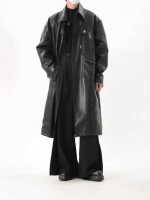 Front full-body view of an oversized black faux leather long rider coat with notched lapel, flap pockets, wide sleeves, and dropped shoulders