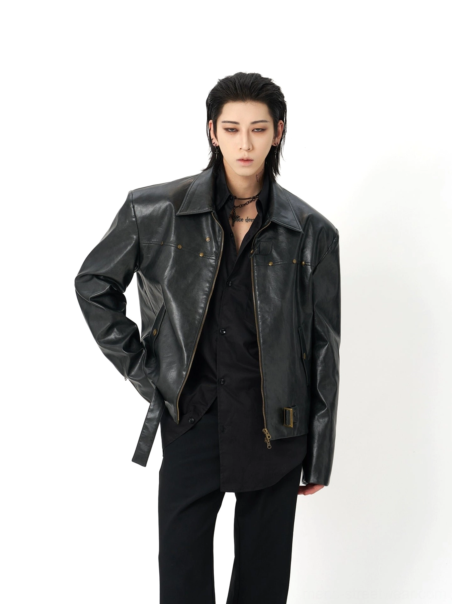 Black oversized faux leather moto jacket shown from a three-quarter front view with notch lapel, bronze zipper hardware, decorative studs, and adjustable waist buckle