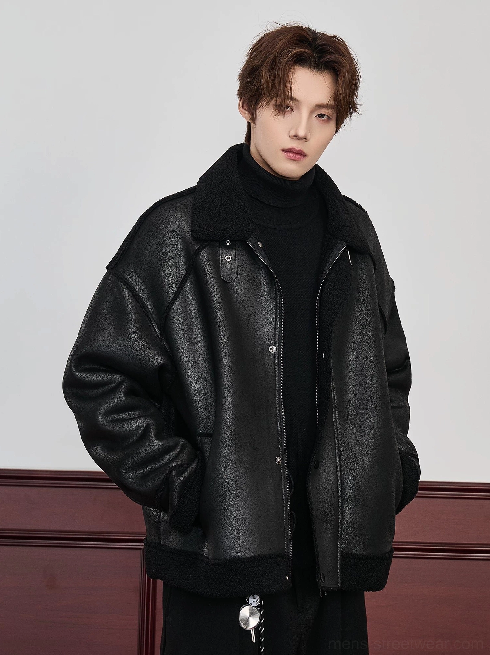 Black oversized faux shearling aviator bomber jacket for men shown in a front three-quarter view with matte faux leather look shell, black shearling collar, and snap-button closure