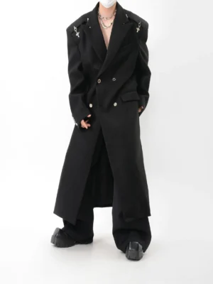 Black oversized gothic streetwear long coat in three-quarter front view featuring cross spike shoulder epaulets and peak lapels