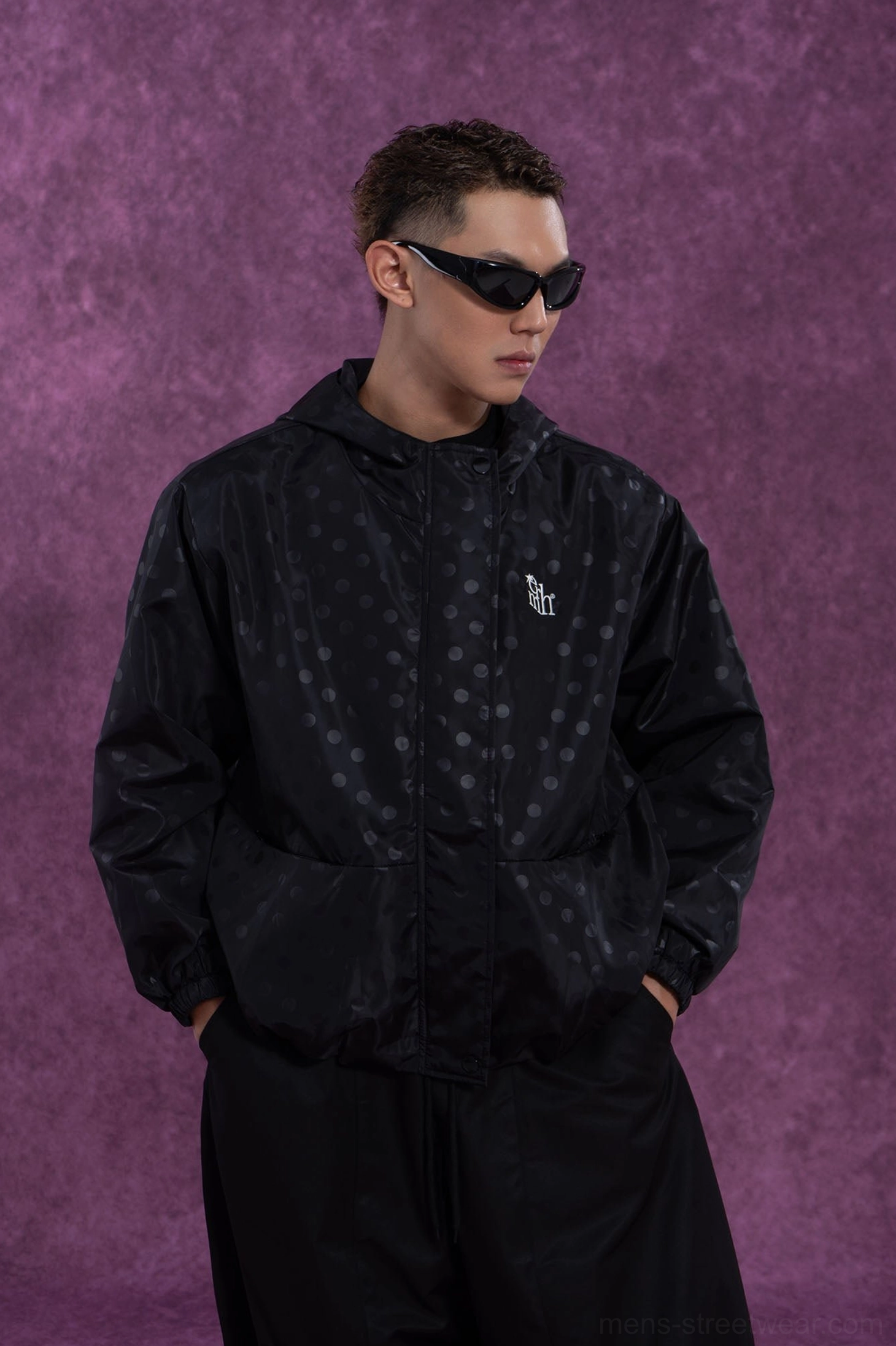 Black oversized hooded streetwear windbreaker with subtle polka dots embroidered chest detail and front pockets