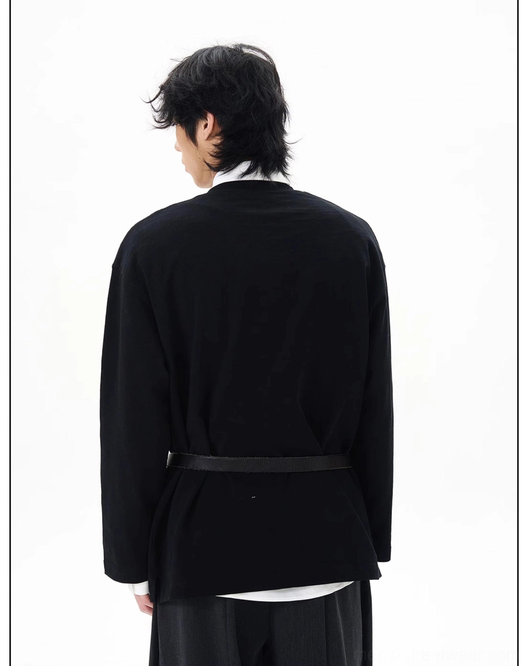 Back view of a black oversized Korean streetwear top with exposed white collared shirt hem and wide-leg black trousers