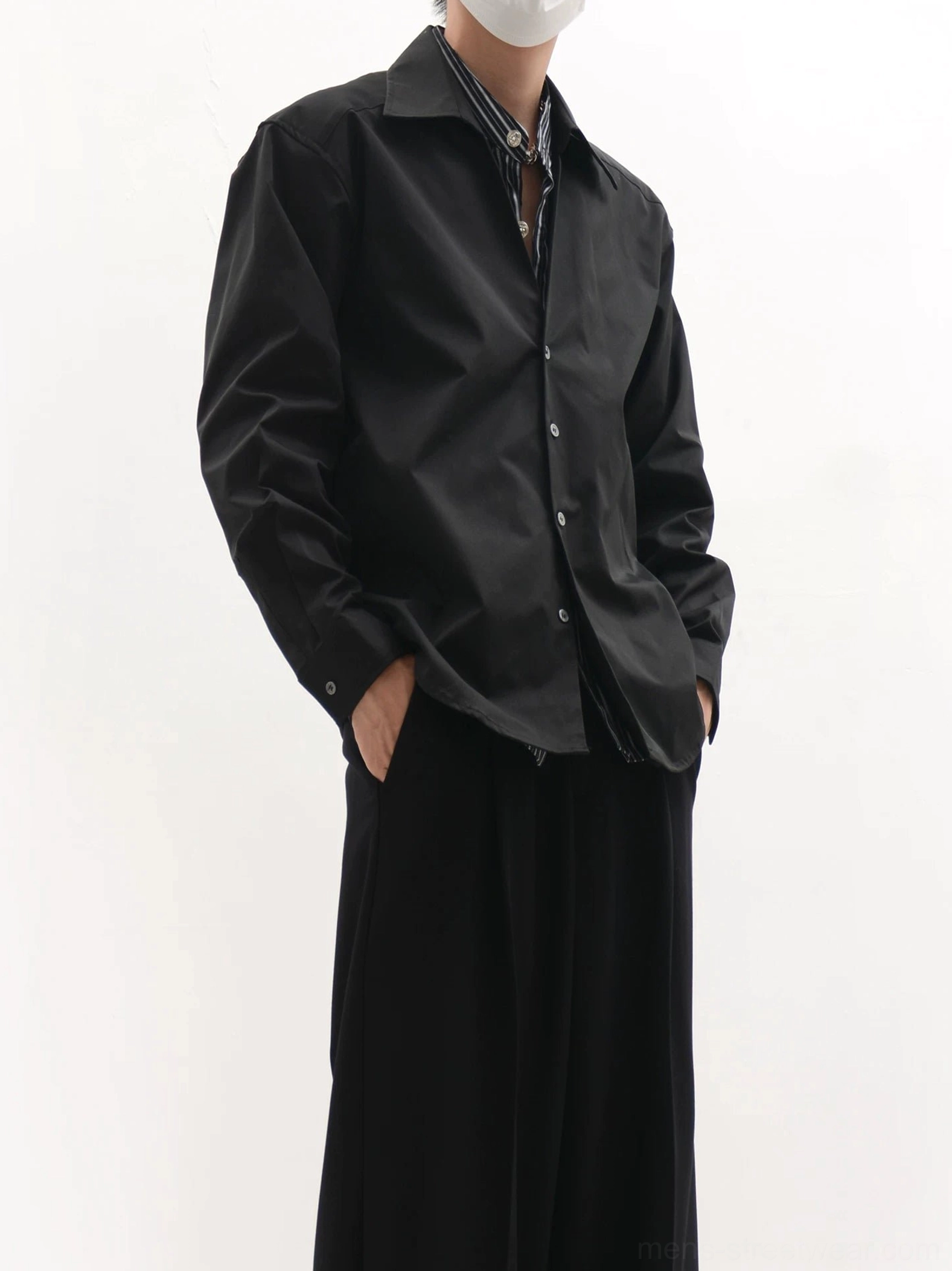 Black oversized longline button-up shirt with raised collar shown in three-quarter view with wide-leg trousers