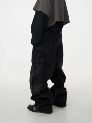 Side rear view of black oversized patchwork baggy jeans featuring waxed denim texture, decorative stitched panels, voluminous wide-leg fit, and modern Korean streetwear styling