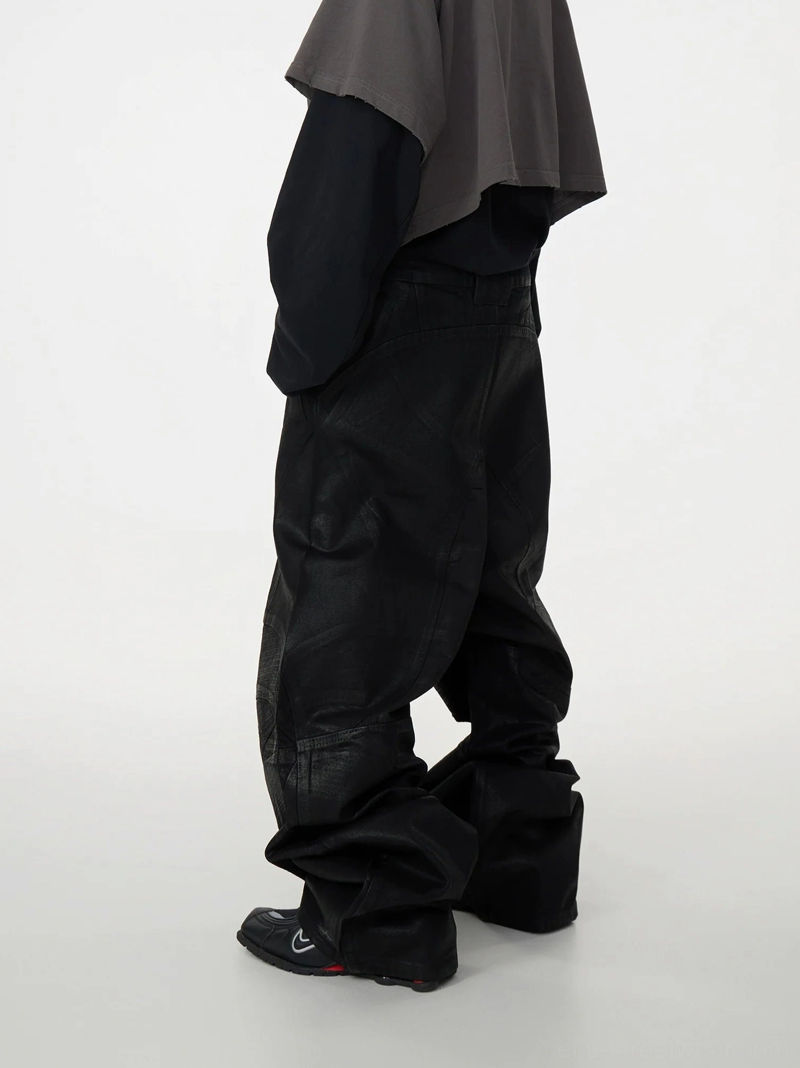 Side rear view of black oversized patchwork baggy jeans featuring waxed denim texture, decorative stitched panels, voluminous wide-leg fit, and modern Korean streetwear styling