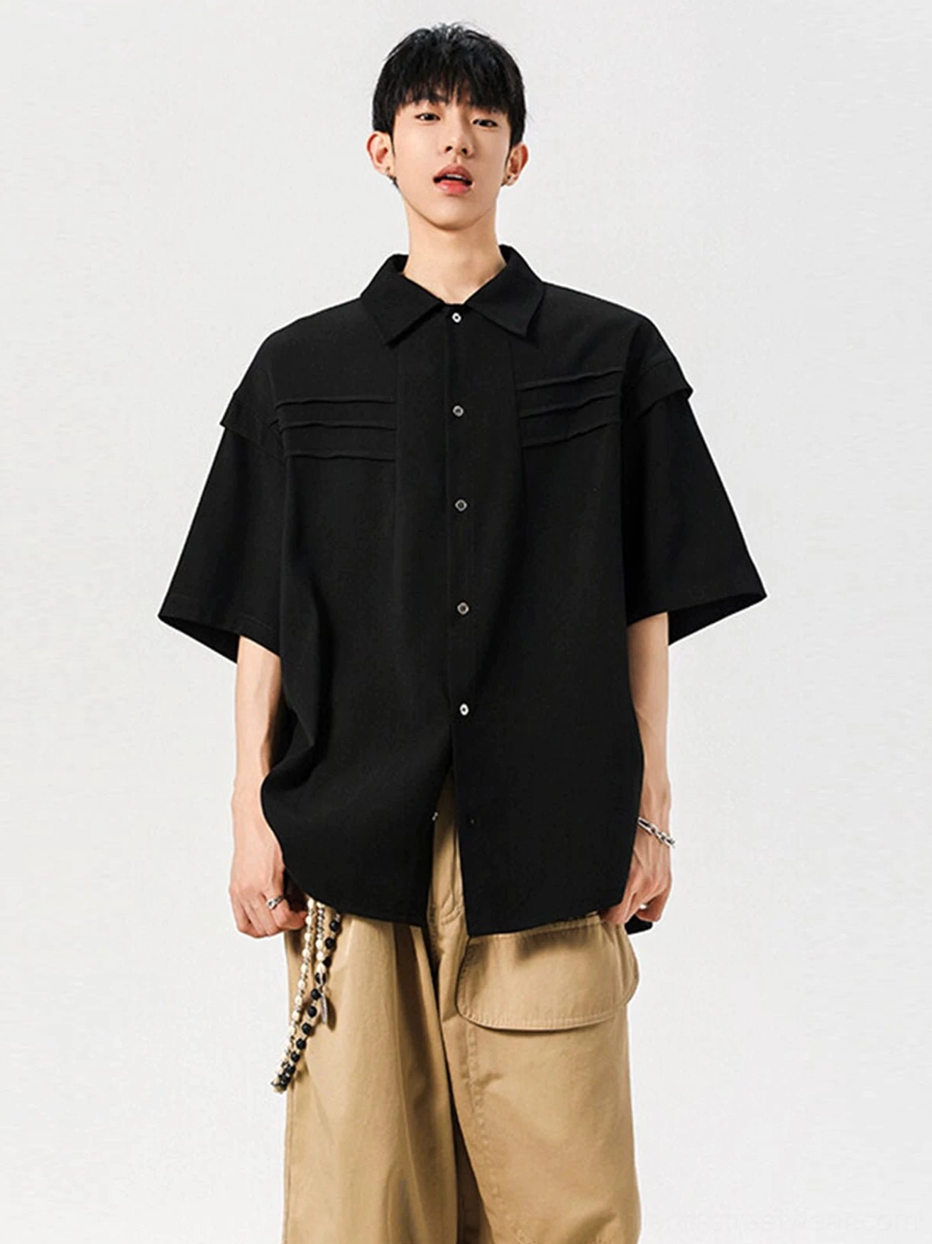 Black oversized pleated chest panel button shirt styled with khaki wide-leg trousers for a modern Korean streetwear outfit