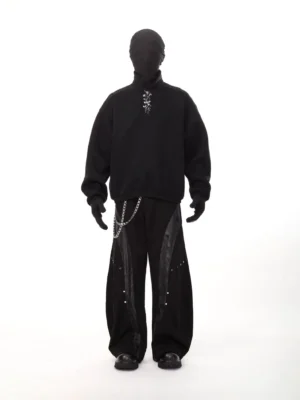Black oversized polo collar sweatshirt front view with metal neckline detail styled with wide leg pants and chain accessories