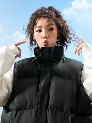 Black oversized puffer vest with high stand collar, neat channel quilting, sleeveless streetwear design, and front zipper