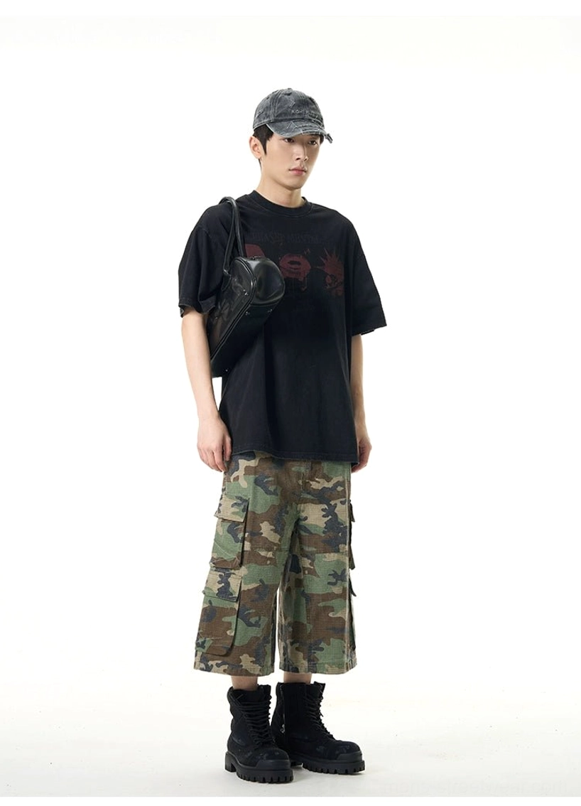 Black oversized punk graphic tee styled with cropped camo cargo pants combat boots and a crossbody bag