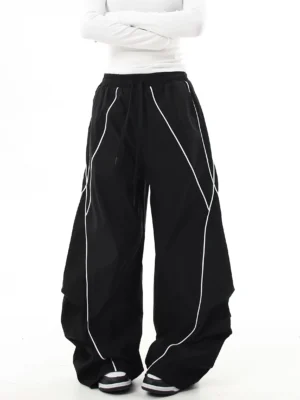 Black oversized reflective cargo pants front view with contrast white diagonal trim, ultra-baggy wide-leg silhouette, elastic drawstring waist, and Korean streetwear styling