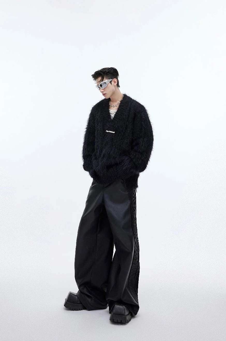 Side view of black oversized shaggy faux-fur V-neck sweater with relaxed silhouette, ribbed neckline, and layered streetwear styling