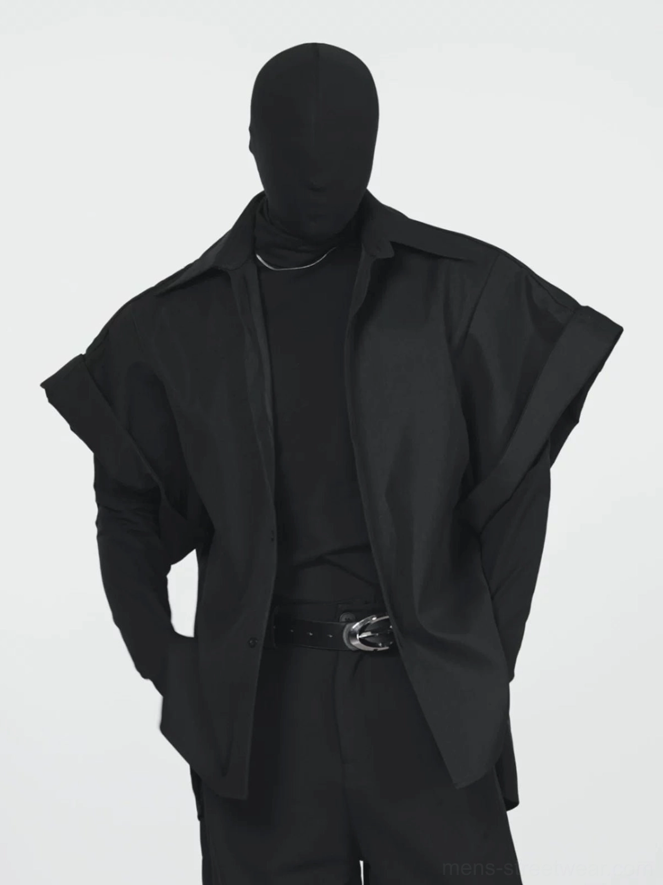 Three quarter view of a black oversized short sleeve shirt jacket with extended shoulders and relaxed avant garde streetwear silhouette