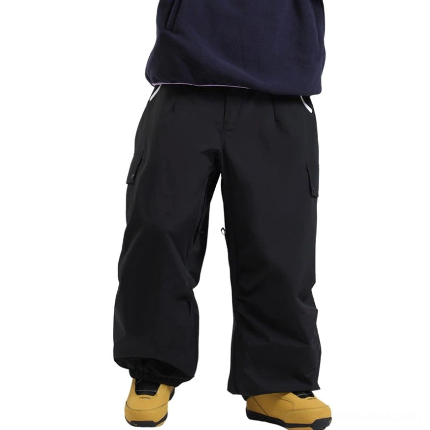 Black oversized ski cargo pants with waterproof outdoor shell, multiple utility pockets, relaxed wide-leg silhouette, high waist, and yellow-brown snow boots