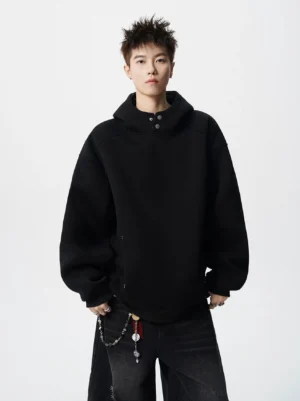 Black oversized snap neck fleece hoodie with high collar and relaxed drop shoulder fit worn with wide leg pants