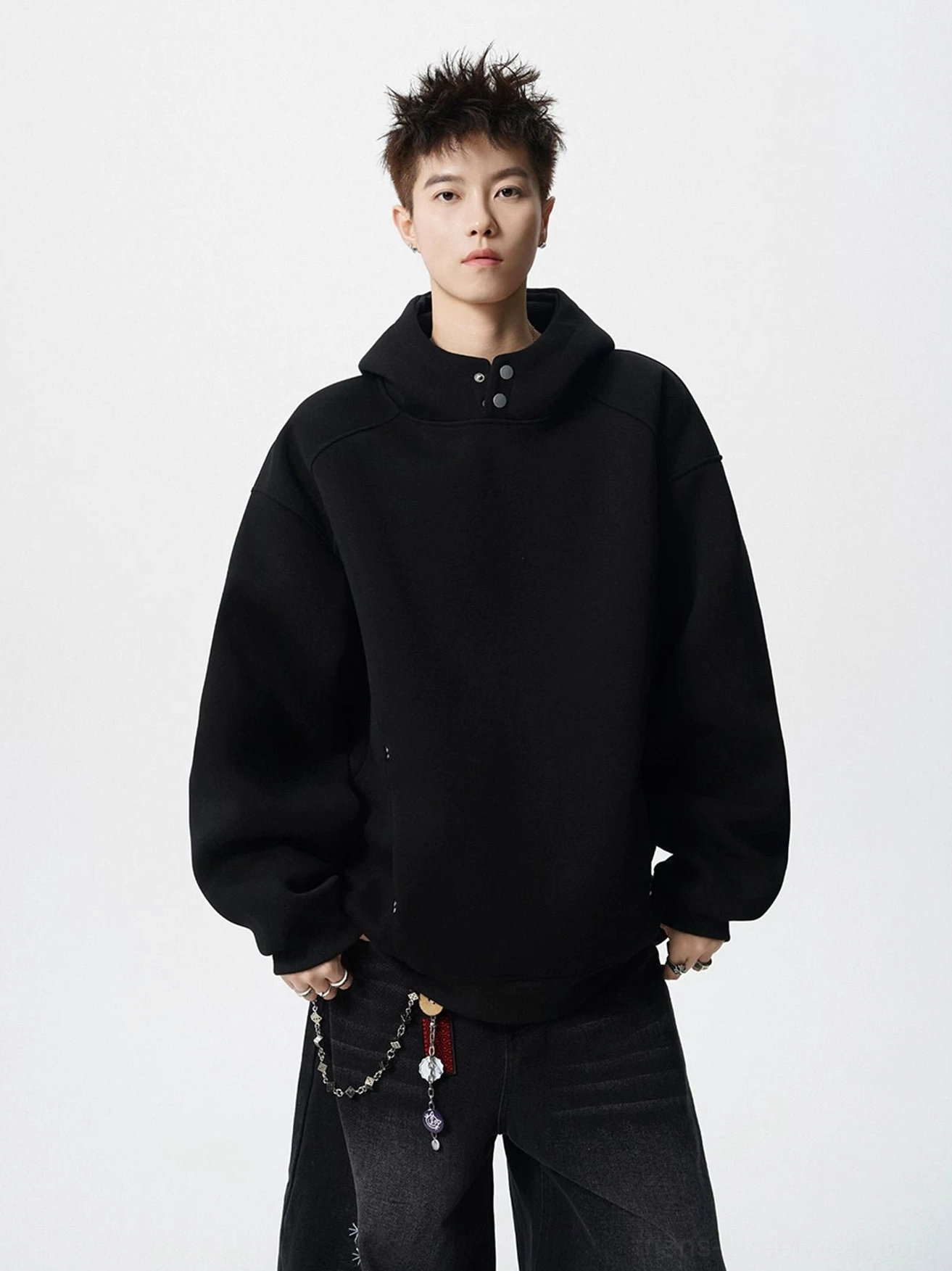 Black oversized snap neck fleece hoodie with high collar and relaxed drop shoulder fit worn with wide leg pants