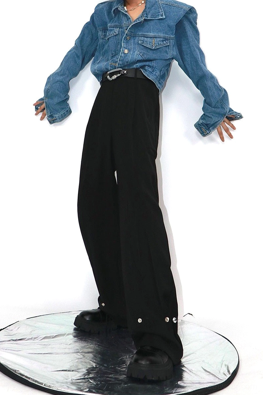 Black oversized loose straight streetwear trousers with high-waisted tailored design, draped fabric, snap cuff details, and cropped denim jacket styling