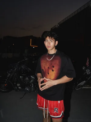 Black oversized graphic streetwear T-shirt with burnt orange handprint chest artwork styled with a silver Cuban chain