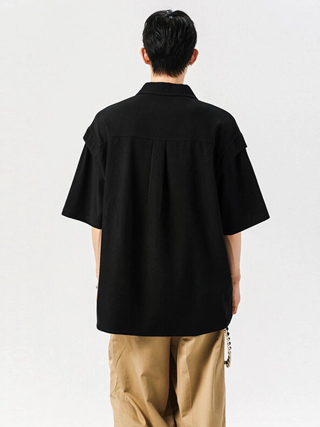 Black oversized streetwear shirt shown from the back with relaxed drop shoulders and a structured back yoke pleat